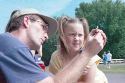 a man demonstrating insulin injection to a young girl